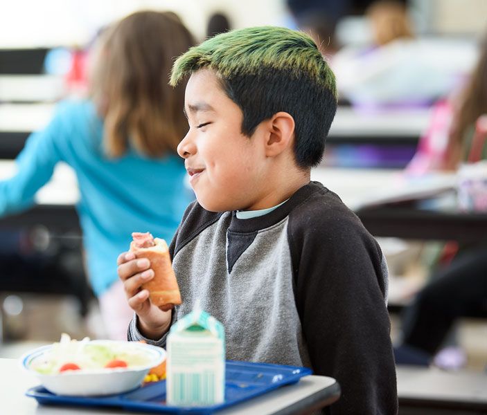 Rusty Rae/News-Register ##
Bruno Hernandez Julio pauses with a smile as he chows down on one of the pigs in a blanket during lunch at Buel Elementary School Friday. Not your father’s wienie wraps, the pigs in a blanket are made with nitrate-free turkey franks and homemade, multi-grain dough.