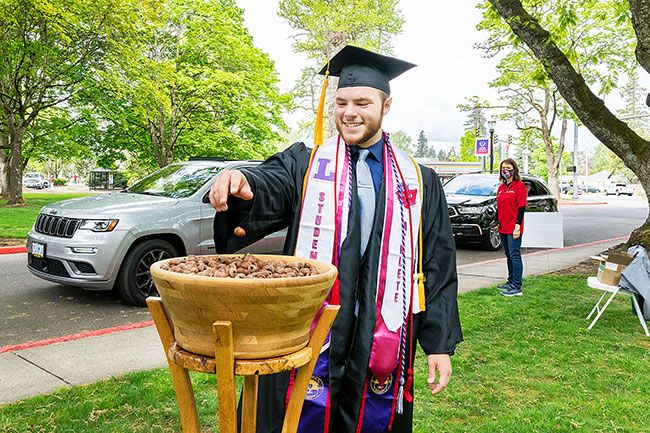 Marcus Larson/News-Register ##
Linfield graduate Connor Ashmun drops his acorn he s been holding onto for four years into the oaken bowl. The acorn represents how students grow over their four years of university classes.