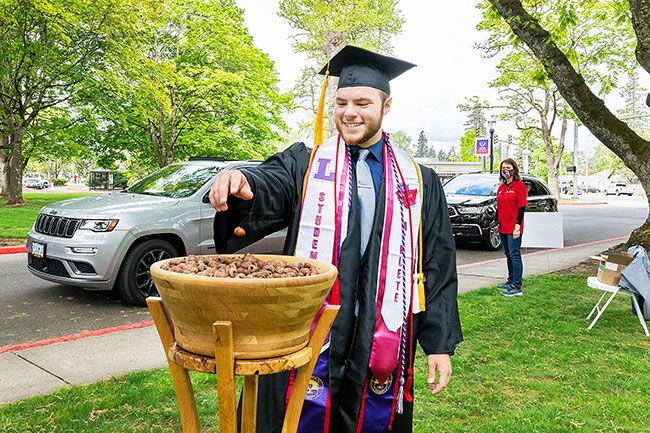 Marcus Larson/News-Register ##
Linfield graduate Connor Ashmun drops his acorn he s been holding onto for four years into the oaken bowl. The acorn represents how students grow over their four years of university classes.