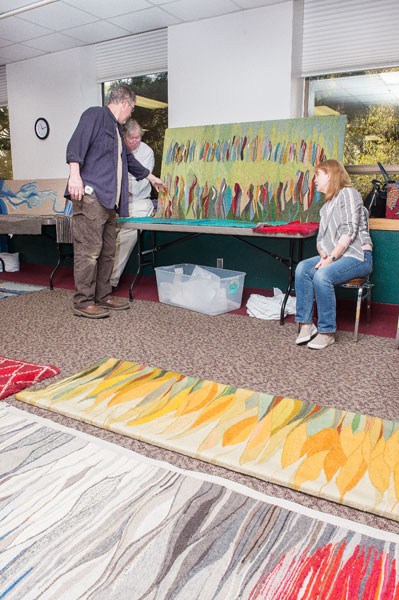 Rusty Rae/News-Register ##  The Johansens display their mother’s tapestries in the McMinnville Community Center so weaving guild members can plan a show. Everyone was drawn to the Native myth piece on the far wall.