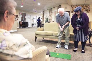 Rockne Roll/News-Register##Warner Kimball demonstrates propper putting to Brookdale Memory Care program coordinator Ashley Rice on his 101st birthday Wednesday, May 4.