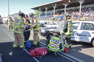 Starla Pointer / News-Register##As community members and students watch from the grandstand, medics assist a  victim  of the mock crash Friday morning.