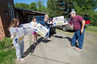 Marcus Larson/News-Register##Sheridan High School principal Dean Rech hands out signs to graduates Alyssa Asuncion, Lilliana Somora, and Victoria Smart last Friday. The idea to hand out signs to Sheridan’s class of 2020 was proposed by math teacher Lucy Bertolo.