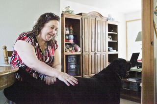 Rockne Roll/News-Register##Elizabeth Wooten pets her dog, Chief, in her new apartment on Southeast Davis Street in McMinnville on Wednesday, May 11. After months of homelessness, Wooten moved in Monday.