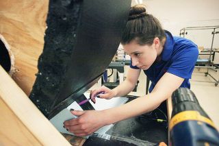 Rockne Roll/News-Register##McMinnville EASA student Kimberly Goss fits a piece of foam to her team’s hoverboard project at the Evergreen Space Museum on Wednesday, May 11. The hoverboard, as large as a sheet of plywood, will be featured in this weekend’s UFO Festival Parade.