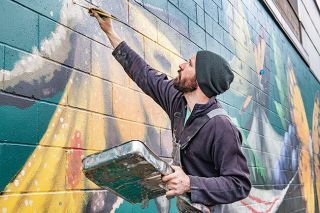 Rusty Rae/News-Register##Visit McMinnville commissioned artist Will Schlough to paint a mural on the side of the Village Quarter building near Third Street and the railroad tracks. Featuring butterflies stealing wine grapes, it’s called “Heist.” He finished the 14-by-69-foot project Tuesday.