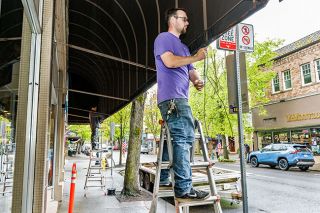 Marcus Larson/News-Register##Leviathyn Cruikshank of Salem Tent & Awning Co. reinstalls the refurbished 46-by-8-foot awning over the Third Street Pizza entrance. The business will host this weekend’s McMinnville Sci-Fi Film Fest.