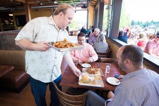 Marcus Larson/News-Register##Owner of the newly opened 1882 Grille, Dustin Wyant, helps serve food to
customers during a busy opening day.