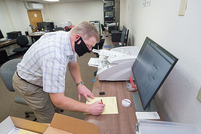 Marcus Larson/News-Register##Yamhill County Clerk Brian Van Bergen fills out a form confirming the voting machine is working properly during a pre-election test last week.