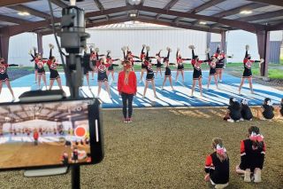 Photo courtesy Stephanie Fox##
In March, the Mac Youth Cheer program sets up its first virtual competition filming. The squad on the mat is the Grizzly Junior Team, doing a run through with Coach Samantha evaluating. Grizzly Mini and Youth teams watch the older kids practice. Head coach Stephanie Fox uses her phone to record their performance. Photo courtesy Stephanie Fox##
In March, the Mac Youth Cheer program sets up its first virtual competition filming. The squad on the mat is the Grizzly Junior Team, doing a run through with Coach Samantha evaluating. Grizzly Mini and Youth teams watch the older kids practice. Head coach Stephanie Fox uses her phone to record their performance.