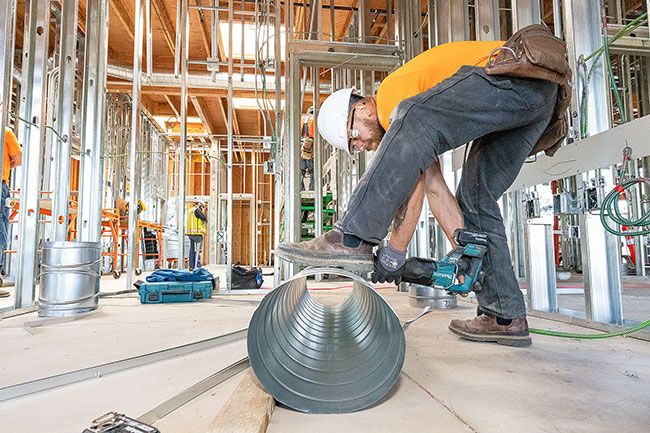 Marcus Larson/News-Register##In May, Chris Patton with Salem Heating & Sheet Metal cuts a spiral duct to install in McMinnville Eye Clinic’s new building on Northeast Cumulus Avenue.