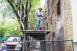 Marcus Larson/News-Register##
Matt Zeller, with Pioneer Water Proofing, tests different chemicals to determine which one will work best for the upcoming brick restoration on the old Taylor Hardware building.