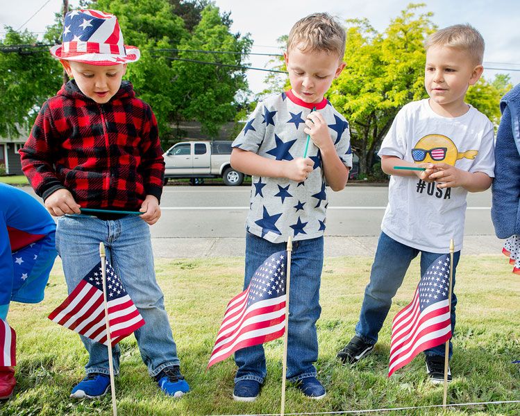 Rockne Roll/News-Register##
From left, Roy Best, 5, Caiden Robinson, 4, and Reid Stapish, 5, rise after planting flags as McMinnville Christian Academy students set up their Memorial Day flag display Friday, May 25.