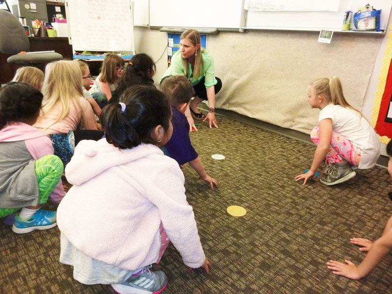 Starla Pointer / News-Register
##Megan Cunningham and her kindergartners try crouching like frogs, then using their strong back legs to jump.