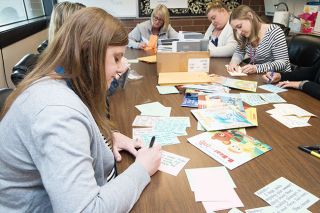 Marcus Larson/News-Register##
Samantha Moorhead, left, Lisa Hill, far right and other Wascher Elementary teachers write personalized letters to students for their summer reading program.