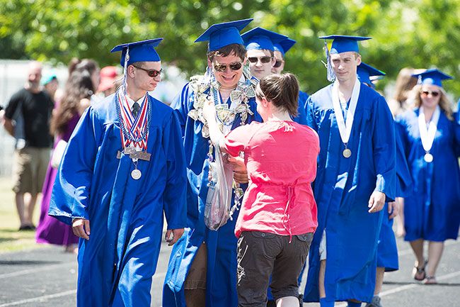 Marcus Larson/News-Register##As graduate Erik
Cropp walks in the parade of graduates, his aunt Dani Bowers left the crowd and placed several congratulatory leis around his neck.