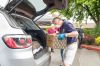 Rusty Rae / News-Register##Jim Botten loads a box of food into a client’s car Friday as a part of the St. James food box giveway. In the background in the red is John Deagas. Also in the background is Father Mike Walker. This event will continue each Friday throughout June.