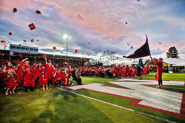 Marcus Larson / News-Register## Graduate Hallie Johnson waves the Senior 2019 flags as her classmates let their caps fly at the conclusion of the ceremony.