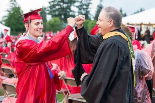Marcus Larson/News-Register##McMinnville High teacher Greg McAnally fist bumps graduate Trey Schiesl as he prepares to receive his diploma during the 2018 MHS graduation ceremony.