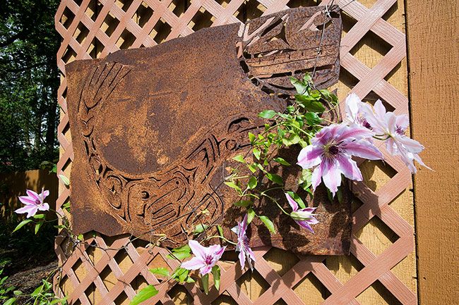 Marcus Larson / News-Register##A clematis climbs a trellis, adding interest to a steel artpiece.