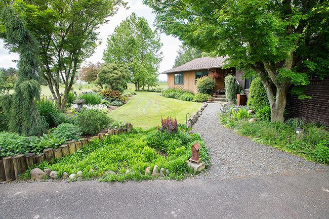 Marcus Larson / News-Register##Paths and lawns wrap around planting beds in the Castles  garden. Here and there are whimsical garden sculptures or mirror balls to add interest.