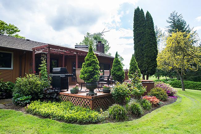 Marcus Larson / News-Register##Bushes and small trees surround John and Edwina’s back deck. When they moved to their property 28 years ago, they started landscaping close to the house, then moved outward.