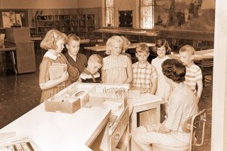 (June 16, 1965) Mrs. Russell Brown, Children’s librarian at the McMinnville Public Library, meets with a group of local youngsters taking part in the summer reading program. The purpose of the program is to encourage summer reading and will continue until Aug. 31.