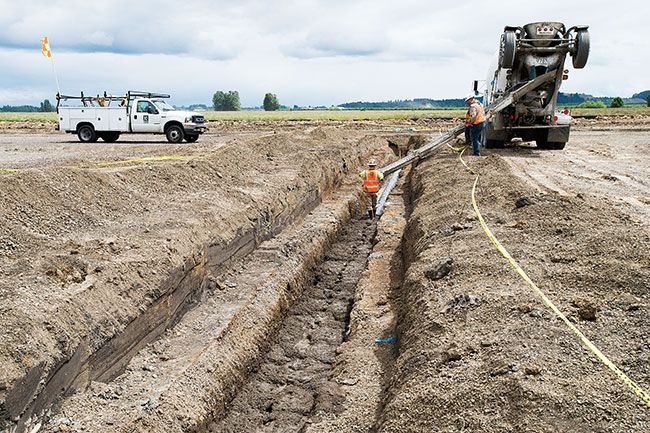 Marcus Larson/News-Register##
Workers cover a large drainage pipe with cement at part of the McMinnville Airport s runway reconstruction project, due to be completed this fall. Planes are using the second runway this summer.