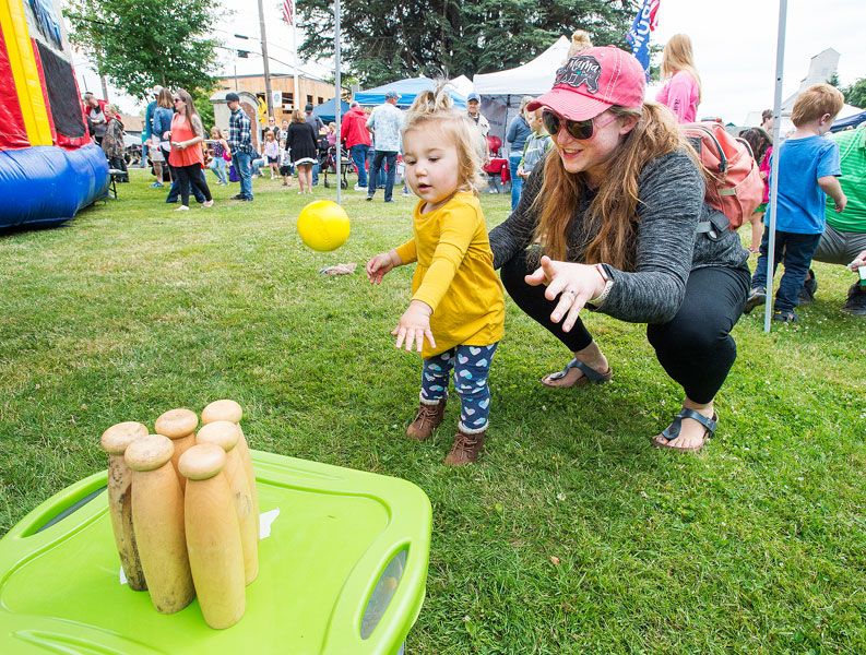 Marcus Larson/News-Register##
Briana Drebin helps her 1-year-old daughter, Juliette, throw a ball at a
set of pins during Carlton Fun Days.
