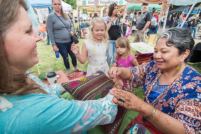 Marcus Larson/News-Register##
Stephanie Godfrey gets a henna design drawn on her arm by artist Carmen
Madrid. They are watched by Godfrey s two daughters, Grace and Emmie,
who also got tattoos.