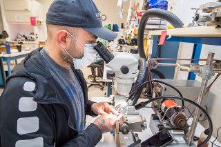 Marcus Larson/News-Register##Applied Physics Technologies employee Jose Cano uses a micro drill to shape a tiny crystal for use in electron microscopes.