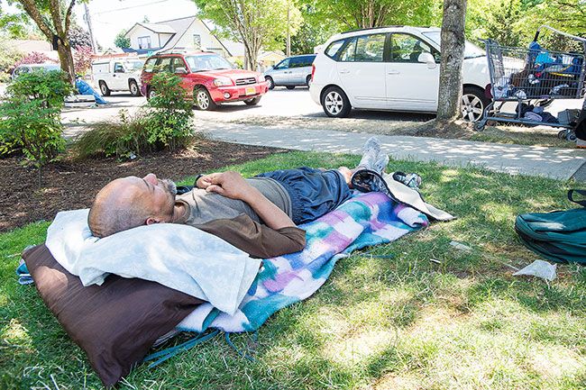 Marcus Larson/News-Register##A homeless man who gave his name as Albert lays down on a makeshift bed on the lawn of the First Presbyterian Church in McMinnville in June.