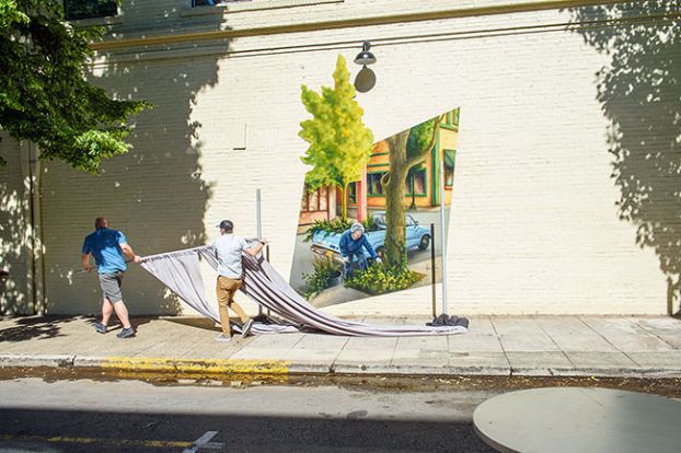 Rusty Rae/News-Register##
Joe Jager of the McMinnville Downtown Association helps to remove curtains from in front of the new mural honoring Rose Mary Caughran. Dozens of people gathered to see the new mural Friday, June 24.