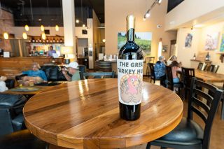 Marcus Larson/News-Register ## 
The Turkey Rama symbol grins from a decorated wine bottle, which will be hidden in the Willamette Valley Vineyards tasting room on Third Street for the July scavenger hunt.
