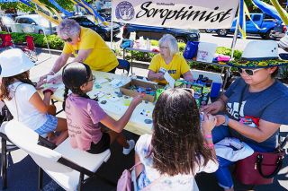 Jake Volz/Eagle Eye Dronography##McMinnville Soroptimists Hermie Kann, left, and Doreen Lybeck Pittman welcome youngsters to the nonprofit s rock painting booth at Turkey Rama s Community Fair.