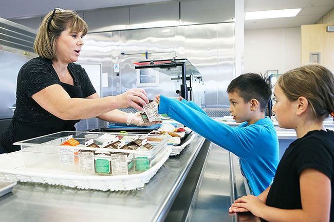 Rockne Roll/News-Register
From left, Sue Buel kitchen manager Karin Nichols serves up lunch to Ronald, 7, and Marjorie Tamber, 9, Wednesday, July 12.