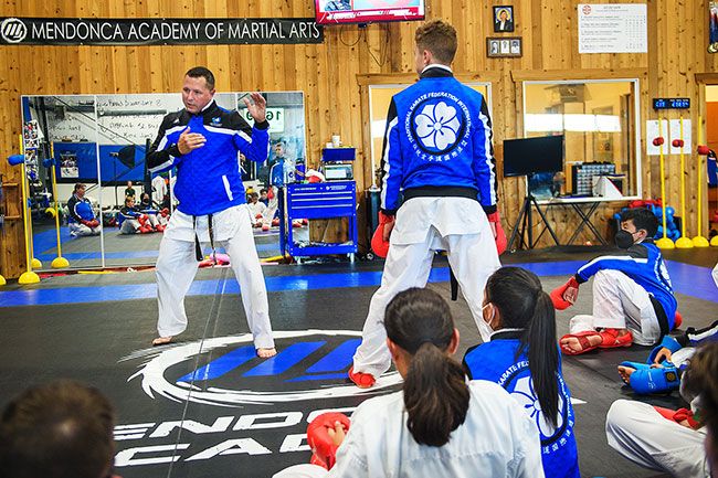 Rusty Rae/News-Register##
Sensei Tony Mendonca demonstrates his karate technique to his students during Wednesday’s training session at Mendonca Academy in McMinnville. His son, Logan, watches from the ring as Tony’s sparring partner.