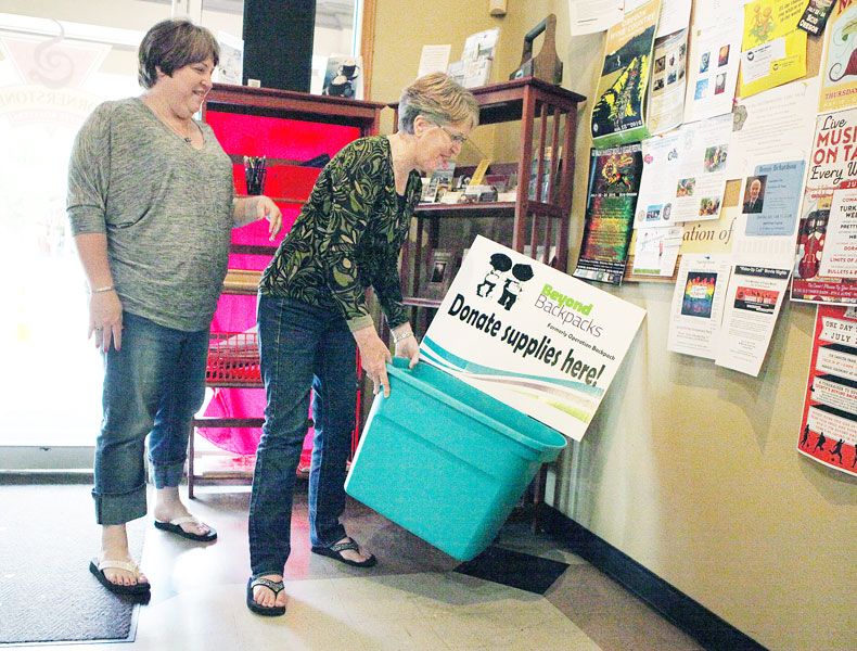 Rockne Roll/News-Register##Maria Mihm, left  and her mother, Celia Kaleta, place a donation bin for Beyond Backpacks at Cornerstone Coffee Roasters in McMinnville on Tuesday. Community members may donate school supplies or cash to the program, which expects to serve 900 children this year.