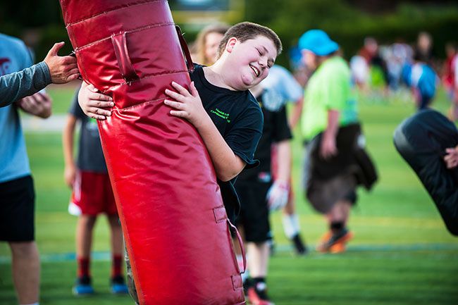 Rusty Rae/News-Register##
Football campers take turns testing themselves against the red dummy during a session of last year s camp