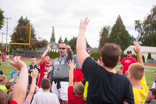 Rusty Rae/News-Register##
McMinnville head football coach Ryan McIrvin leads junior players in a drill during last year s camp.