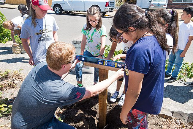 Marcus Larson / News-Register##Teacher David Larson helps students make sure the post that holds the library is straight.