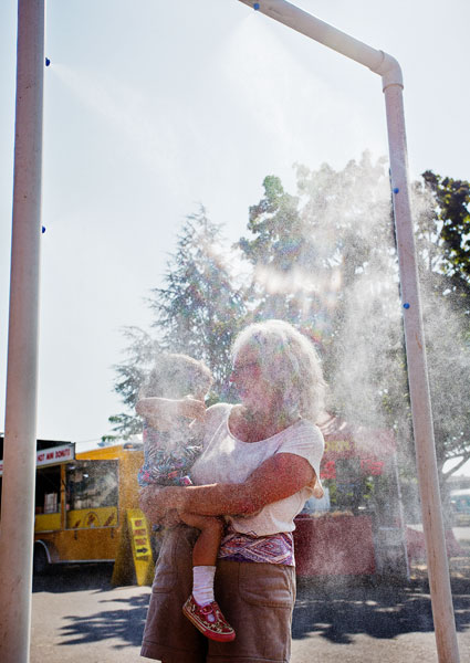 Rockne Roll/News-Register##Jean Carter and her granddaughter Suzanne Carter, 3, pause under one of the misters set up at the county fairgrounds to combat the searing heat.