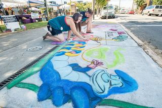 Marcus Larson/News-Register##
Chalk artists Beth Porter and Megan Gometz work to touch up their Alice in Wonderland themed piece.