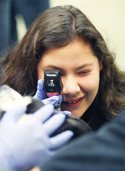 Rockne Roll/News-Register##
Jordan Montario marvels at her view of a dog’s eye. The McMinnville High School junior is using a special, lighted scope to see the retina and rear wall of Dori Anne’s eye during the canine wellness exams at the Summer Veterinary Experience.