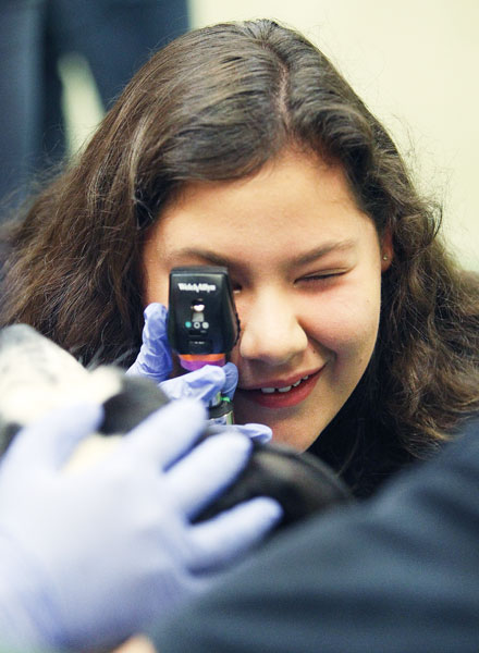 Rockne Roll/News-Register##
Jordan Montario marvels at her view of a dog’s eye. The McMinnville High School junior is using a special, lighted scope to see the retina and rear wall of Dori Anne’s eye during the canine wellness exams at the Summer Veterinary Experience.