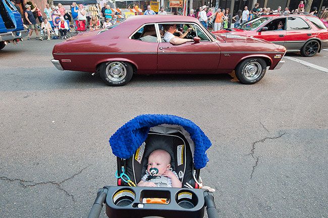 Marcus Larson / News-Register
Four-month-old Graydin Alexander has a confused look on his face as several classic cars drive by behind him making loud engine noises.