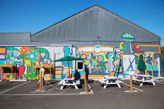 Rusty Rae/News-Register##Artist Bryan Nichols and friends work on the mural at the east end of the Boho Building on Southeast First Street between Galloway and Irvine. The scene shows images related to the building’s tenants and to McMinnville, such as the Spruce Goose and a UFO.