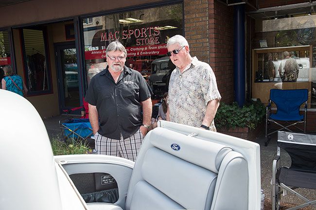 Rusty Rae/News-Register##
Royal Kenton, an upholster by trade,  chats with one of the many cars fans who stopped by on Saturday to look at his 1932 white Ford 5-Window Coupe. He  s telling the visitor how he restored the rumble seat.