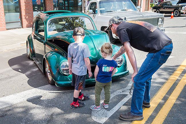 Rusty Rae/News-Register##
Jesse Robinson, of Sheridan, shows his two children, Jeb and Addi, a classic Volkswagen Beetle during the Cruising McMinnville car show.