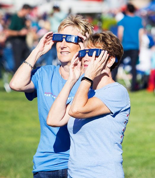 Rockne Roll / News-Register##Terri Longwell, left, of Rocky Point, Mexico, and Dianne Zika of Palm Springs, California, look through their eclipse glasses toward the sun during the event at Evergreen Aviation Museum Aug. 21. Local businesses are collecting used eclipse glasses to send to children who ll see a solar event in 2019.
